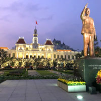 Stately City Hall at dusk with a bronze illuminated statue of Ho Chi Minh